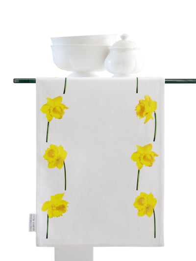 Daffodils table runner table setting with runner hanging over.